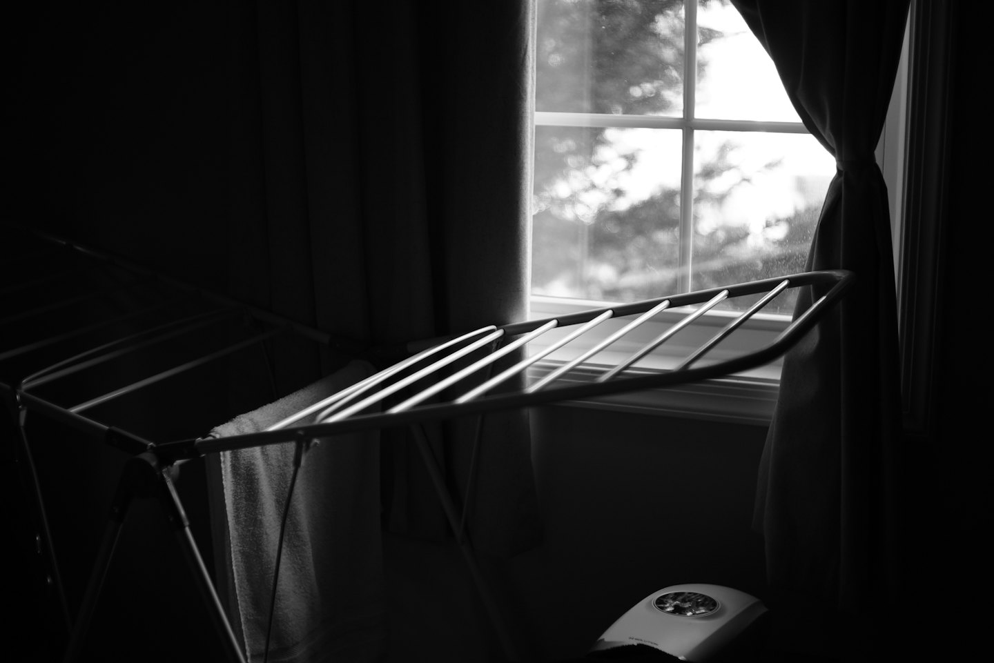 A white towel hangs on a drying rack by a window.